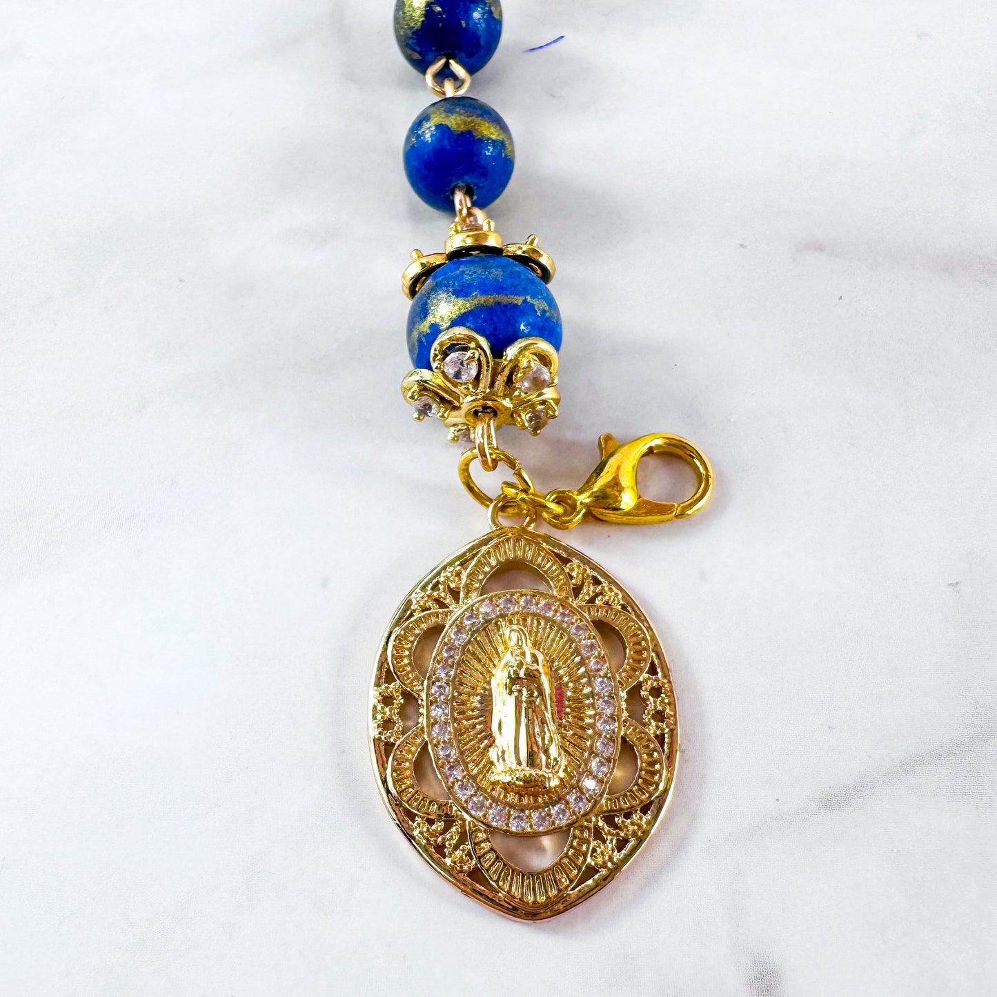Luxury Catholic rosary bracelet handcrafted with natural Lapis Lazuli gemstone beads, a gold-tone cross with zirconia accents, and a Lady of Guadalupe medal. Adjustable beaded bracelet perfect for prayer, religious gifts, Confirmation, bridesmaid gifts, or everyday devotion. Made in Edmonton, AB, Canada.