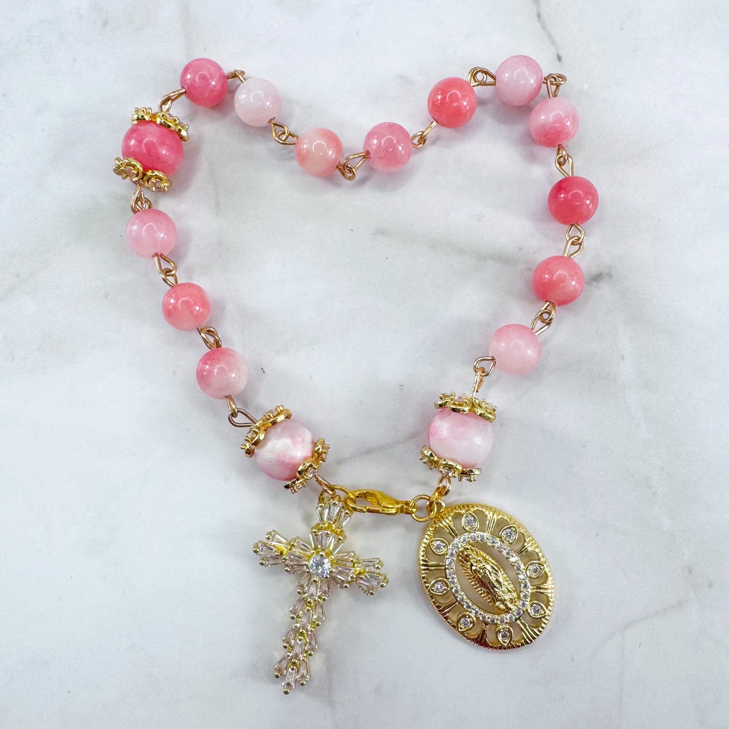 Luxury Catholic rosary bracelet handcrafted with natural pink persian jade gemstone beads, a gold-tone cross with zirconia accents, and a Lady of Guadalupe medal. Adjustable beaded bracelet perfect for prayer, religious gifts, Confirmation, bridesmaid gifts, or everyday devotion. Made in Edmonton, AB, Canada.