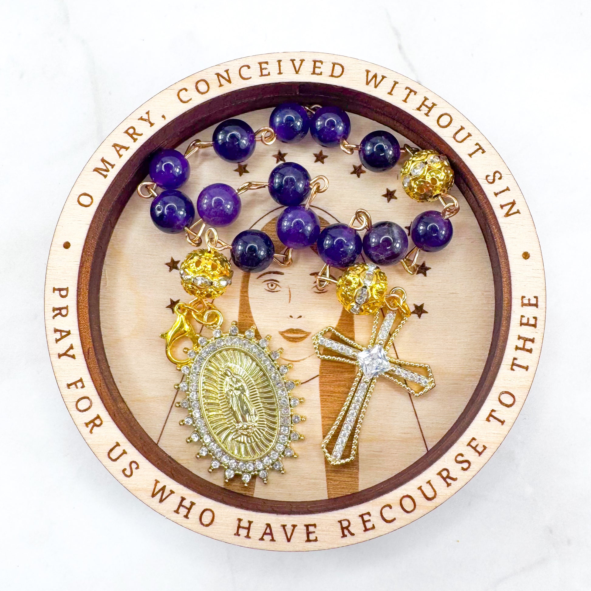 Handmade Catholic rosary bracelet with amethyst beads, sparkling gold cross, and Our Lady of Guadalupe medal. Perfect for gifts or prayer. Made in Edmonton, AB, Canada.