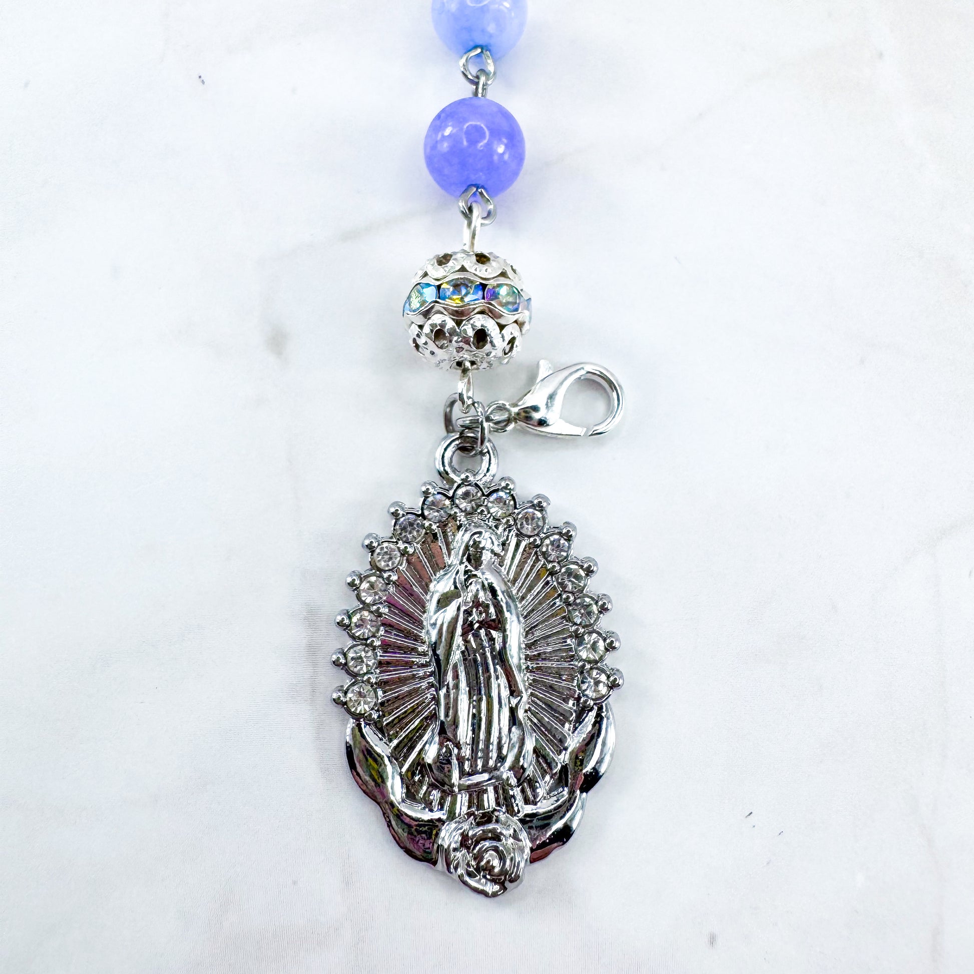 Luxury Catholic rosary bracelet handcrafted with natural Periwinkle Blue Angelite gemstone beads, a silver-tone cross with zirconia accents, and a Lady of Guadalupe medal. Adjustable beaded bracelet perfect for prayer, religious gifts, Confirmation, bridesmaid gifts, or everyday devotion. Made in Edmonton, AB, Canada.
