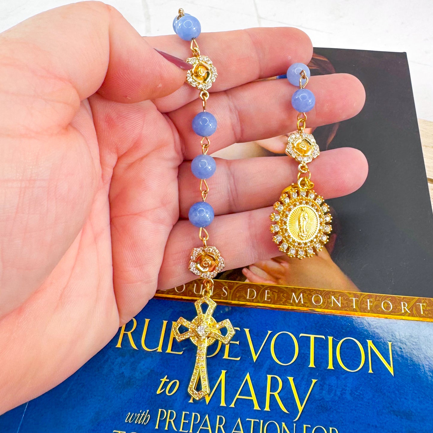 Luxury Catholic rosary bracelet handcrafted with natural blue quartz gemstone beads, a gold-tone cross with zirconia accents, and a Lady of Guadalupe medal. Adjustable beaded bracelet perfect for prayer, religious gifts, Confirmation, bridesmaid gifts, or everyday devotion. Made in Edmonton, AB, Canada.
