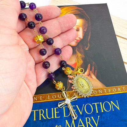 Handmade Catholic rosary bracelet with amethyst beads, sparkling gold cross, and Our Lady of Guadalupe medal. Perfect for gifts or prayer. Made in Edmonton, AB, Canada.