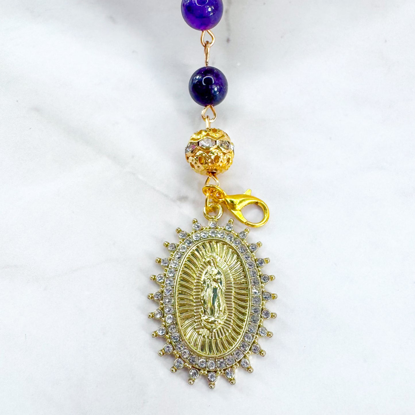 Handmade Catholic rosary bracelet with amethyst beads, sparkling gold cross, and Our Lady of Guadalupe medal. Perfect for gifts or prayer. Made in Edmonton, AB, Canada.