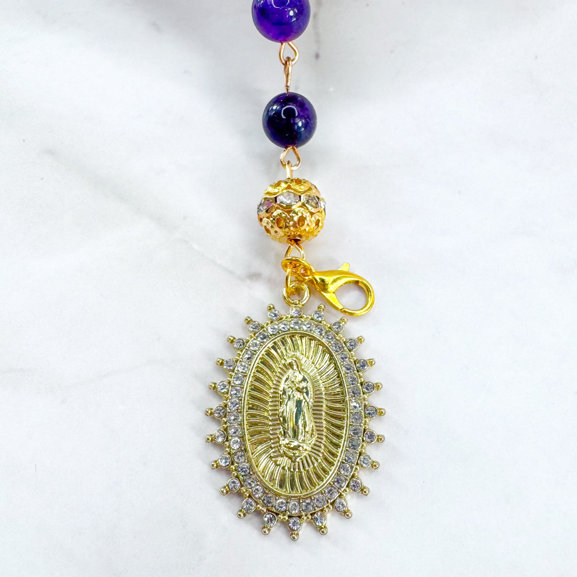 Handmade Catholic rosary bracelet with amethyst beads, sparkling gold cross, and Our Lady of Guadalupe medal. Perfect for gifts or prayer. Made in Edmonton, AB, Canada.