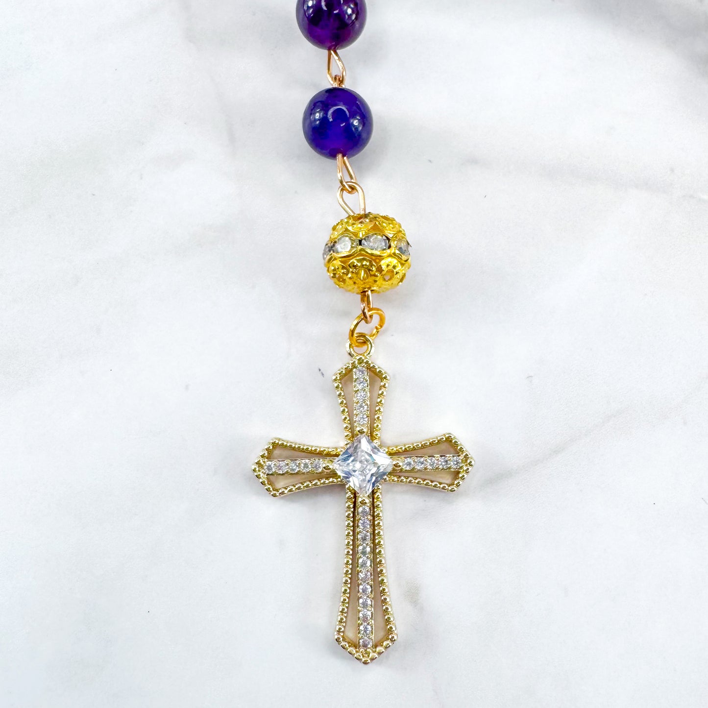 Handmade Catholic rosary bracelet with amethyst beads, sparkling gold cross, and Our Lady of Guadalupe medal. Perfect for gifts or prayer. Made in Edmonton, AB, Canada.
