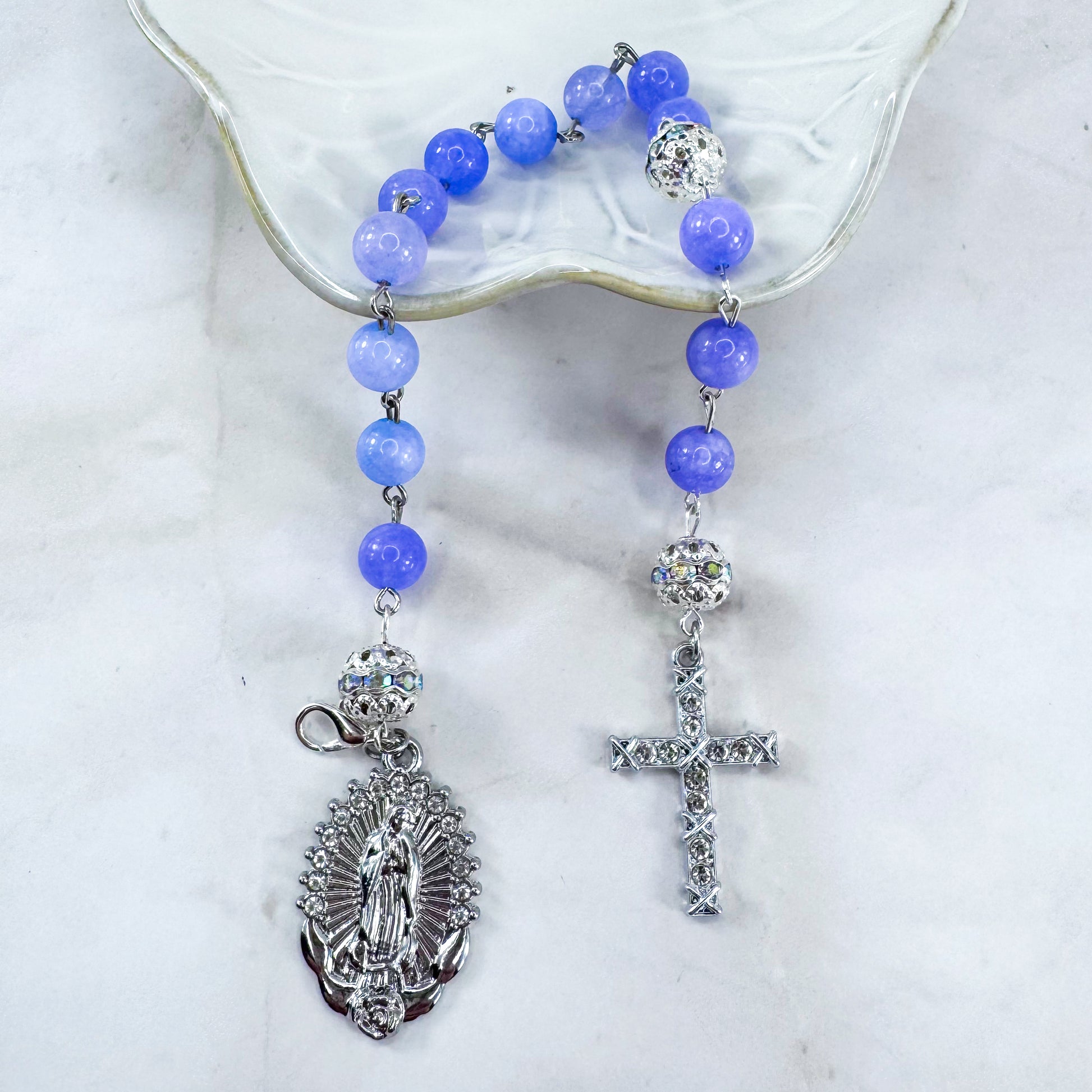 Luxury Catholic rosary bracelet handcrafted with natural Periwinkle Blue Angelite gemstone beads, a silver-tone cross with zirconia accents, and a Lady of Guadalupe medal. Adjustable beaded bracelet perfect for prayer, religious gifts, Confirmation, bridesmaid gifts, or everyday devotion. Made in Edmonton, AB, Canada.