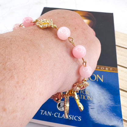 Luxury Catholic rosary bracelet handcrafted with natural rose quartz gemstone beads, a gold-tone cross with zirconia accents, and a Lady of Guadalupe medal. Adjustable beaded bracelet perfect for prayer, religious gifts, Confirmation, bridesmaid gifts, or everyday devotion. Made in Edmonton, AB, Canada.